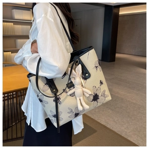 Détail d'un sac cabas en toile avec motifs floraux noirs et breloque lapin mignonne