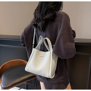 Vue détaillée d'une femme portant le sac seau beige avec une texture en cuir grainé