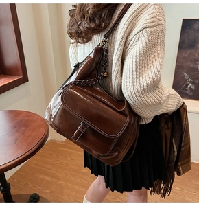 Détail d'un grand sac bandoulière vintage marron avec coutures contrastées blanches et texture huilée