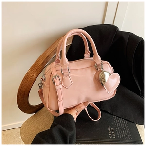 Close-up of pink Boston bag with silver hardware and a heart leather pendant