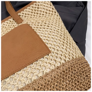 Detail of woven straw tote bag with brown faux leather pocket and neat stitching