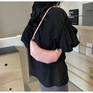 Detail of pink croissant bag with vertical quilting and adjustable shoulder strap
