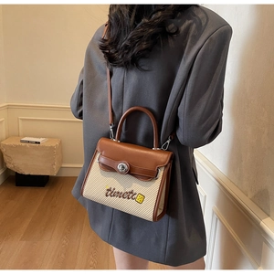 Detail of a brown leather and beige woven crossbody bag with embroidery and metal lock