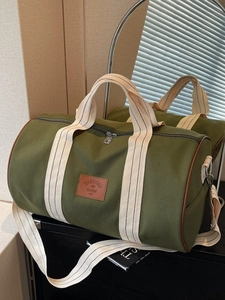 Large dark green canvas travel duffel bag with brown trim and striped shoulder straps
