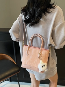 Sac seau rose brillant avec charme en peluche et bandoulière porté par le mannequin