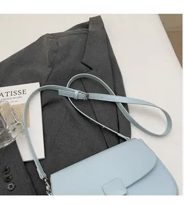 Close-up of light blue leather crossbody bag showing smooth strap and square buckle detail