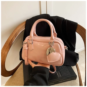 Detailed view of pink glossy leather bowling bag with heart charm and shoulder strap