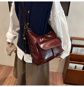 Détail du sac à bandoulière vintage rouge foncé avec clochette dorée et gland à franges