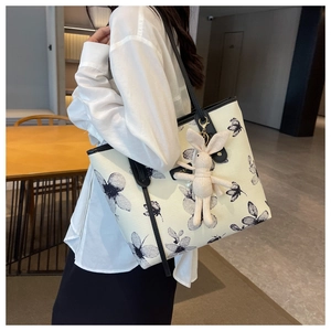 Modèle portant un grand cabas en toile à motifs floraux noirs avec charme lapin en peluche