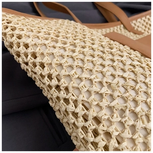 Close-up of woven straw tote bag with brown leather handles and beige texture detail