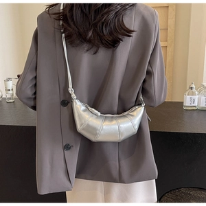 Detailed view of silver crescent crossbody bag with pleated stitching on model back