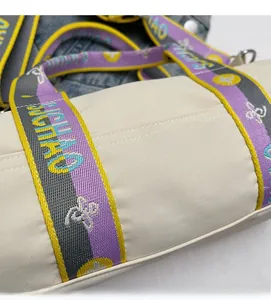 Détail du sac cylindrique blanc cassé montrant le nylon et la bandoulière tissée