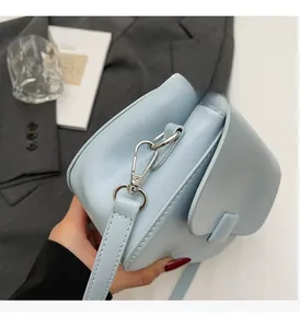 Detail of light blue leather crossbody bag with polished silver metal buckles and strap