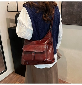 Vue latérale d'un grand sac à bandoulière en cuir rouge foncé avec poche à boucle