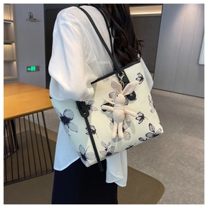 Détail du sac cabas en toile avec imprimé floral, anses en cuir et porte-clés lapin