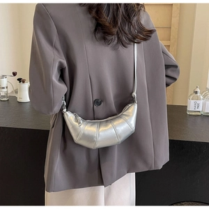 Detail of silver crescent croissant bag with quilted faux leather on a crossbody strap