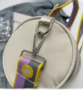 Détails des finitions métalliques argentées et bandoulière tissée sur sac cylindre beige