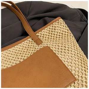 Detailed macro view of beige straw weaving and premium brown leather pocket on a tote bag