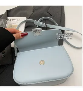 Detail view of light blue crossbody bag featuring a silver magnetic buckle and smooth leather