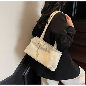 Detail of cream shoulder bag with belt buckles, key pendant and side coin purse