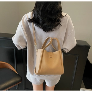 Gros plan du sac seau en cuir beige grainé avec bandoulière et poignées doubles