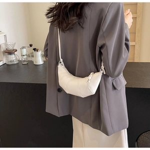 Detail shot of a white matte leather croissant crossbody bag with vertical stitching