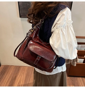 Détail d'un sac hobo vintage rouge foncé en cuir texturé avec une poche à boucle devant