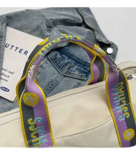 Détail du sac à main en similicuir crème avec une poignée tissée colorée brodée