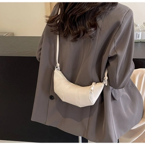 Detail view of a beige crescent crossbody bag with quilted segments on a model's back