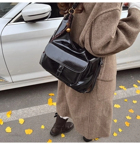 Détail d'un sac à bandoulière noir brillant vintage avec boule dorée et sangle