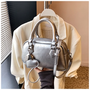 Detail of silver metallic bowling bag with heart pendant on soft blazer background