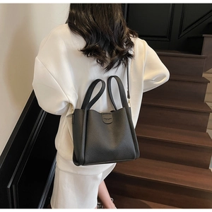 Détail du sac seau en cuir grainé noir avec poignée structurée et logo discret