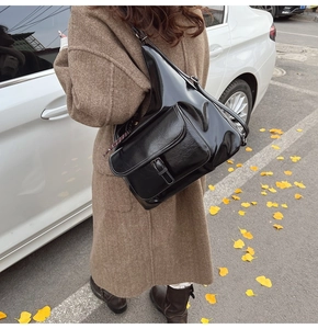 Détail d'un sac messager noir vintage avec coutures blanches contrastées et boucle