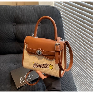 Detail of woven straw and brown leather handbag with silver twist lock and embroidery