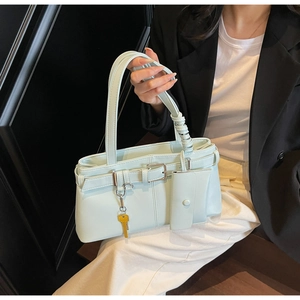 Close-up of mint green leather tote bag with unique shoulder strap and yellow key charm