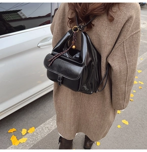 Détail d'un sac à dos en similicuir noir brillant avec anneau métallique et cordon