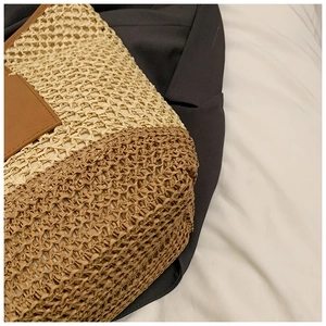 Close-up of woven straw handbag featuring beige textures and brown leather detail