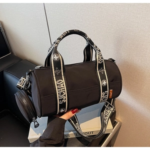 Détail du sac à main cylindrique noir en tissu avec mini porte-monnaie amovible et sangle