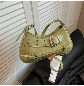 Détail du sac baguette en cuir vert avec œillets argentés et boucles en métal