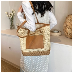 Close-up of stylish straw woven tote bag with brown leather straps and detailed texture