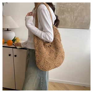 Detail of a brown crochet knit shoulder bag with hollow flower patterns in a home setting