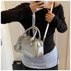 Detailed view of silver metallic bowling bag with heart charm for crossbody wear