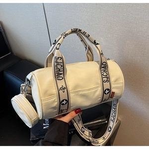 Détail du sac cylindrique blanc cassé avec bandoulière fleurie et porte-monnaie