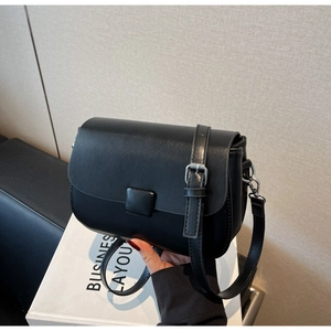 Detail view of the black faux leather crossbody bag with silver buckle and adjustable strap
