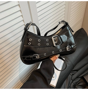 Détail du sac hobo en cuir verni noir avec œillets métalliques et lanières à boucles