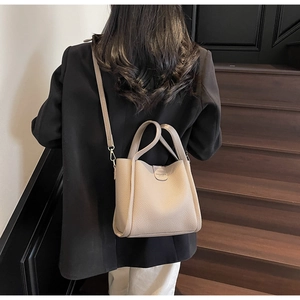 Détails du sac seau en cuir grainé beige avec des finitions métalliques dorées