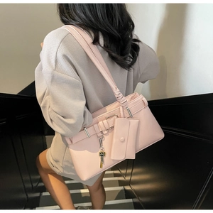 Close-up of soft pink PU leather shoulder bag with decorative strap knot and metal buckle