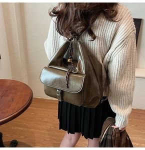 Détail d'un sac à dos vintage vert olive en similicuir texturé avec breloque