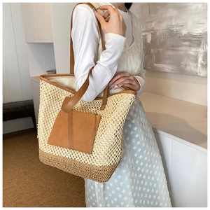 Detail of the woven straw tote bag with brown PU leather patch and shoulder straps