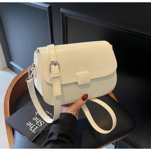 Detail of a creamy white leather crossbody bag with adjustable strap and silver hardware